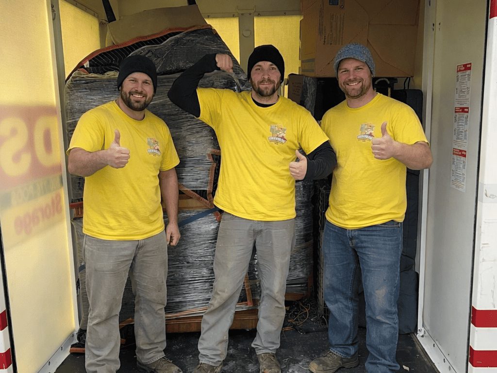 Three Hercules movers giving a thumbs up inside a PODS container they have just loaded