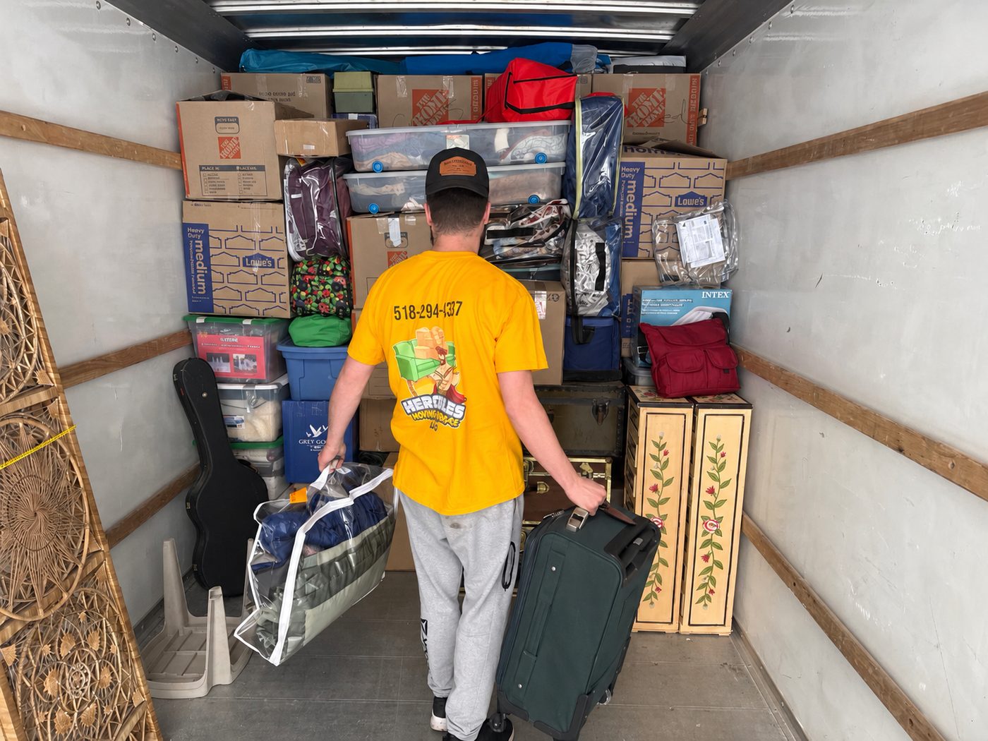 A Hercules mover building a tight wall of boxes and furniture inside a truck
