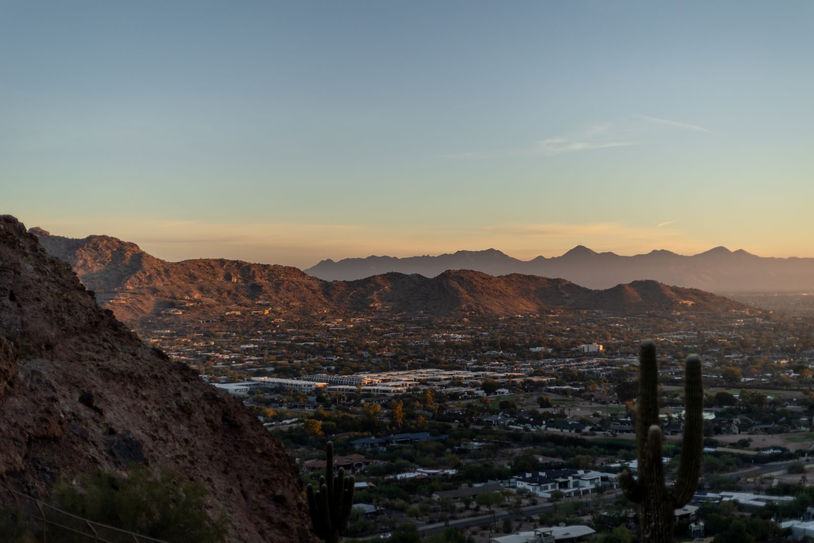 Downtown Phoenix at sunset seen from a desert hillside with saguaro cacti in the foreground