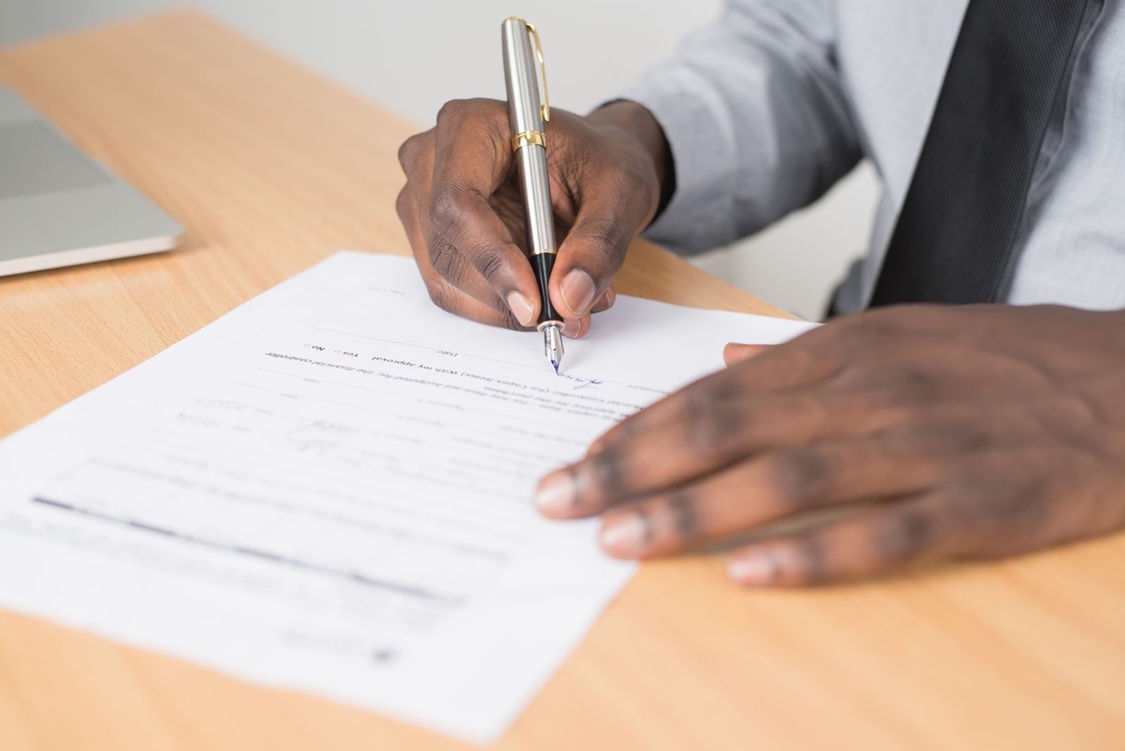 A hand signing a printed form with a pen