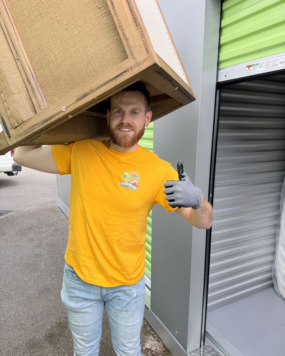Liam carrying a cabinet on his shoulder outside a storage unit